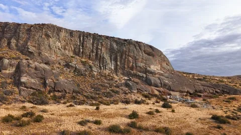 Rugged rock formation and steep cliff face under a blue sky 库存影片 342049734