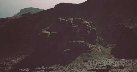 Rugged rock formations under a cloudy sky in a remote landscape Illustrazione stock