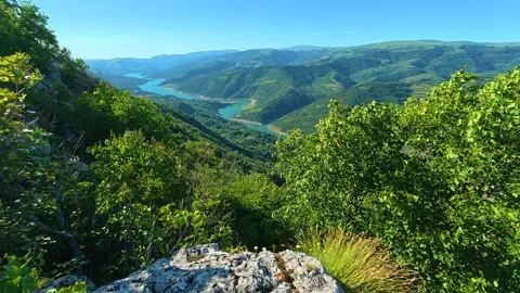 Rugged rock juts from emerald forest edge. Kozji Kamen viewpoint, Serbia Stock Footage 342340693
