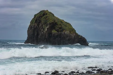 Rugged sea stack and surf on Madeira coast under overcast skies Foto stock