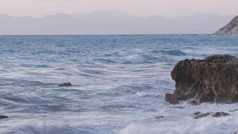 Rugged Seaside Rocks Surrounded by Foamy Ocean Waves at Sunset Stock Footage 336916952