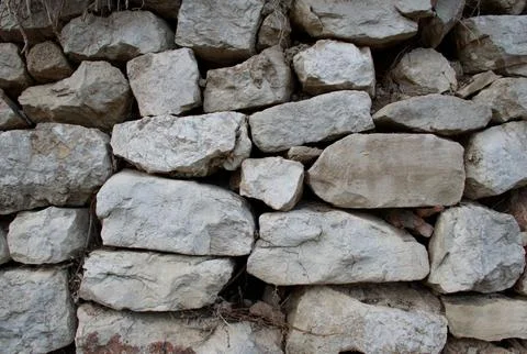 Rugged stacked stone wall texture with natural, irregular rock surfaces. Stock Photos