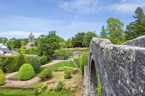 Rugged stone arch frames a tranquil garden vista Stock Photos