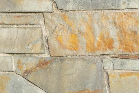 Rugged stone wall with a multi-colored structure with cracks and damage Stock Photos