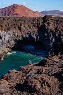 Rugged volcanic landscape with deep blue water nestled in rocky cany. Lanzarote 스톡 사진