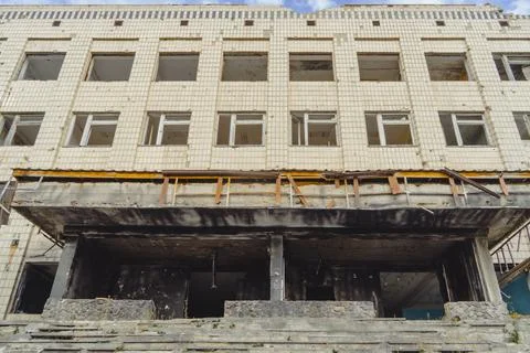Ruined building facade with broken windows and fire damage from military action Stock Photos