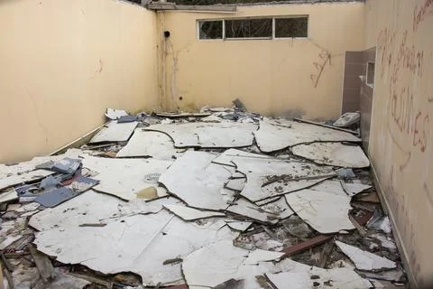 Ruined house by collapsed ceiling. Broken wall, bricks on the ground. Stock Photos