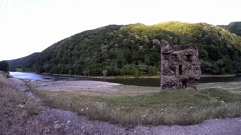 Ruins of a medieval stone tower built next to a river flowing beneath Stock Footage 69833030
