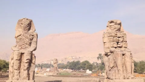 Ruins of the two giant statues of pharoah with mountains in the background Stock Footage 255587573