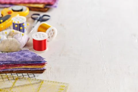 Ruler, cutting mat, stack of multi-colored pieces of fabric, pincushion, spool Stock-Fotos