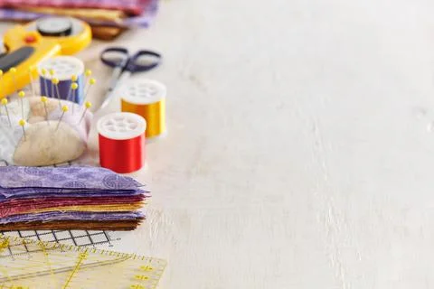 Ruler, cutting mat, stack of multi-colored pieces of fabric, pincushion, spoo Stock Photos