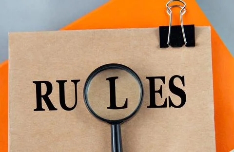 RULES - word on a brown sheet with a magnifying glass in the center Stock Photos
