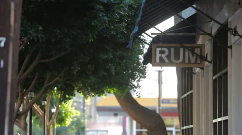 Rum Sign Hangs Under a Blue Awning and Green Trees on a Windy Day Stock Footage 61839647