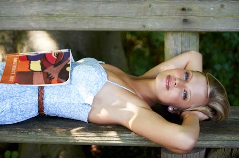 Ruminating on a great read. a beautiful young woman with a book lying down on a Stock Photos