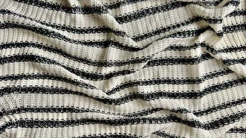 Rumpled black and white striped knitted blanket showcases soft cozy ribbed te Foto stock
