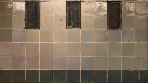 Run down tiled green wall with exhaust grille Stock Photos