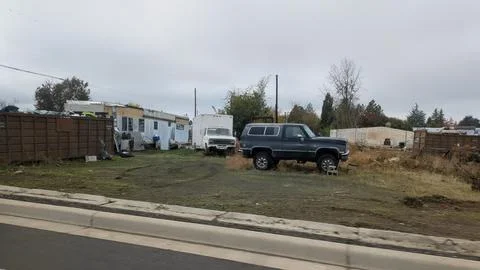 Run-down trailer next to a massive brown trash bin overflowing Stock Photos