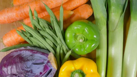 A run of multiple raw vegetables with a cleaver on a worktop. 스톡 동영상 146967280