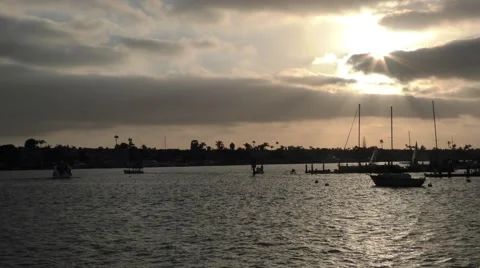 Run rays streaking through afternoon clouds pilons yachts in silhouette shot Stock Footage 67467620