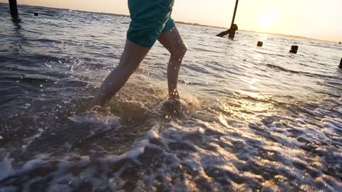 Run at seaside beach, evening sun in the background, slow motion Stock Footage 76887502