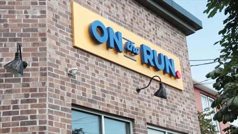 On the run writing caption text yellow blue sign on brick wall with light Stock Footage 250278720