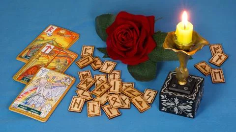 Rune divination against a backdrop of a candle and a rose flower Stock Photos