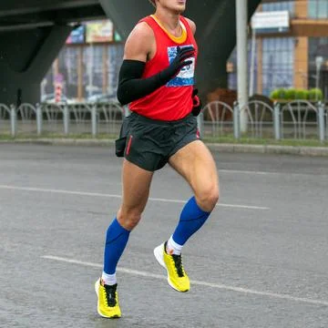 Runner athlete in compression socks and long sleeve running marathon in cold Stock Photos