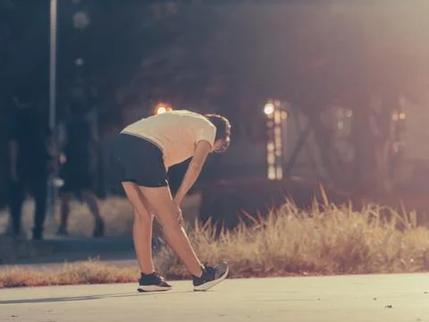 Runner Bending Over Catching Breath on Park Path at Golden Hour, Fitness Brea Stock Photos