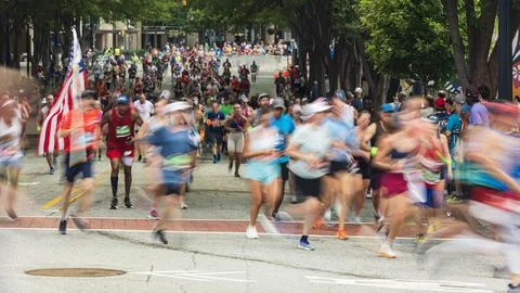 Runner carrying American flag motion blurs at Peachtree Road Race Foto stock