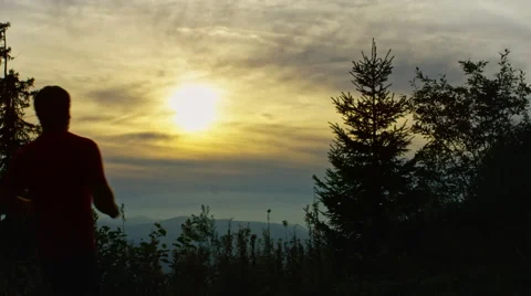 Runner celebrates  while in the mountains with a beautiful sun set and view Stock Footage 63026754