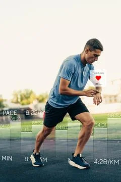 Runner checks heart rate during training session in a park on sunny day Stock Photos