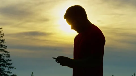 Runner checks his hand held device while in the mountains with a beautiful sun Stock Footage 63011354