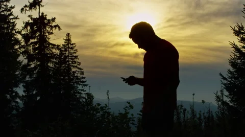 Runner checks his hand held device while in the mountains with a beautiful sun Stock Footage 63015970