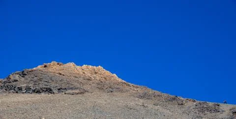 Runner climbing difficult slope of Teide volcano against blue sky Stock Photos