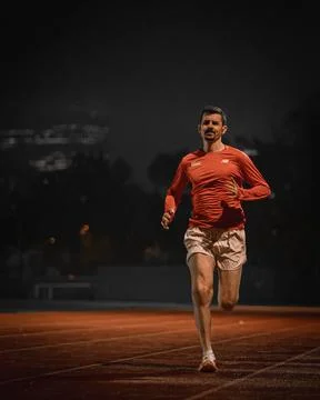 Runner coming straight towards the camera along track lanes at night Stock Photos