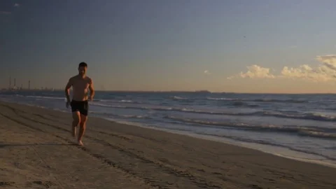 Runner doing workout on the beach resting and running again Stock Footage 70610405