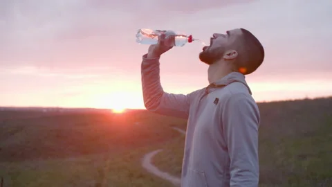 Runner drinking water after workout in field Stock-Footage 153565539