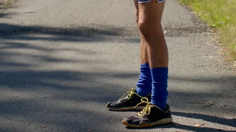 A Runner Engaged in Stretching Exercises on the Road in Athletic Gear Stock Footage 318922549
