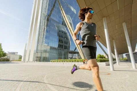 Runner enjoys a sprint in front of a modern building on a sunny day Stock Photos