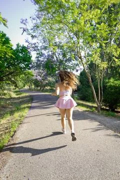 Runner enjoys a sunny day on a path surrounded by green trees and flowers in a Stock Photos