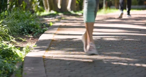 Runner is entering from right, is passing dark-pants walker on shaded brick path Stockbeeldmateriaal 342596389
