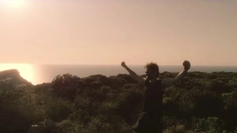 Runner exulting on top of a cliff in front of the ocean Stock Footage 78017984
