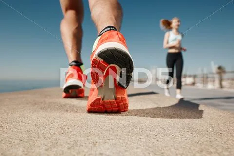 Runner feet running on road closeup on shoe. Sportsman fitness sunrise jog wo Stock Photos