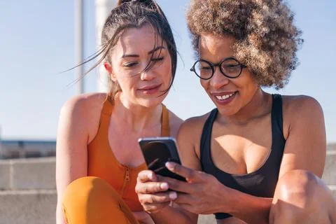 Runner friends using a mobile phone outdoors Stock Photos