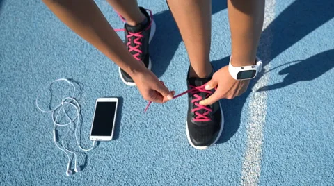 Runner getting ready tying running shoes with smartwatch earphones and phone Stock Footage 61390215