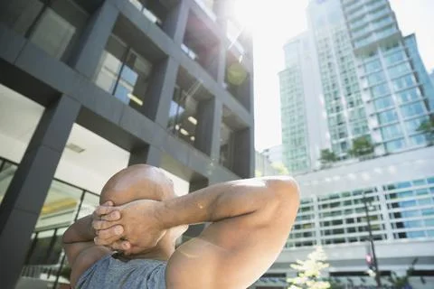 Runner with hands behind head looking up at city highrise Stock Photos