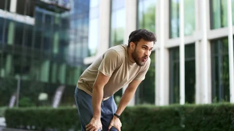 Runner has shortness of breath during a run along a city street. Athlete feels  Stock Footage 306306071