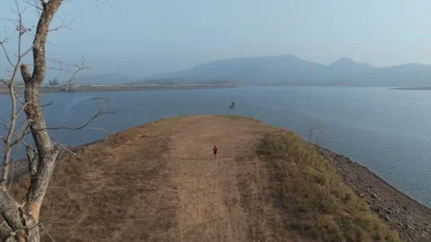 Runner Jogging Along Narrow Dam Causeway Surrounded by Reservoir Water and Stock Footage 337165752