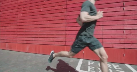 Runner jogging past red wall and 'Fire Exit' sign. Stock-Footage 58872607