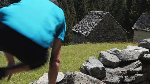 Runner jumps a wall and run in the meadow Video stock 114176000